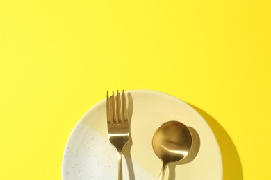 Photo of Stylish plate and cutlery on yellow background, top view. Space for text