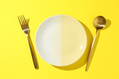 Photo of Stylish plate and cutlery on yellow background, flat lay