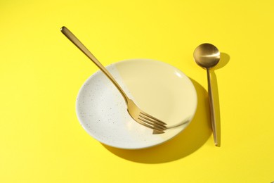 Photo of Stylish plate and cutlery on yellow background, above view