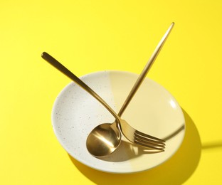 Photo of Stylish plate and cutlery on yellow background, closeup