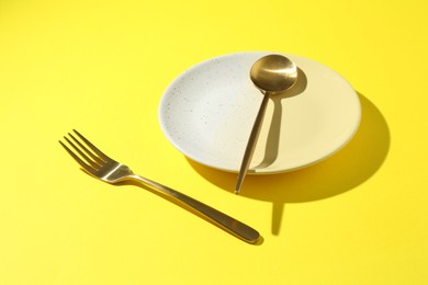 Photo of Stylish plate and cutlery on yellow background, closeup