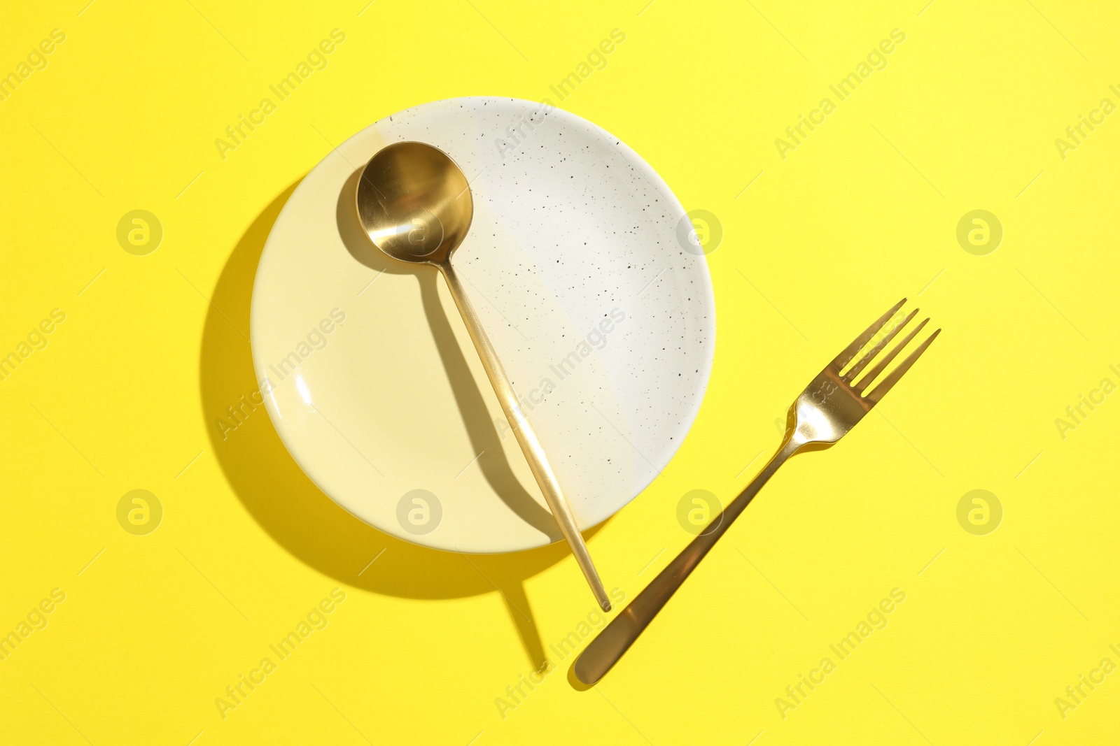 Stylish plate and cutlery on yellow background, flat lay Photo of Stylish plate and cutlery on yellow background, flat lay