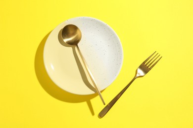 Photo of Stylish plate and cutlery on yellow background, flat lay