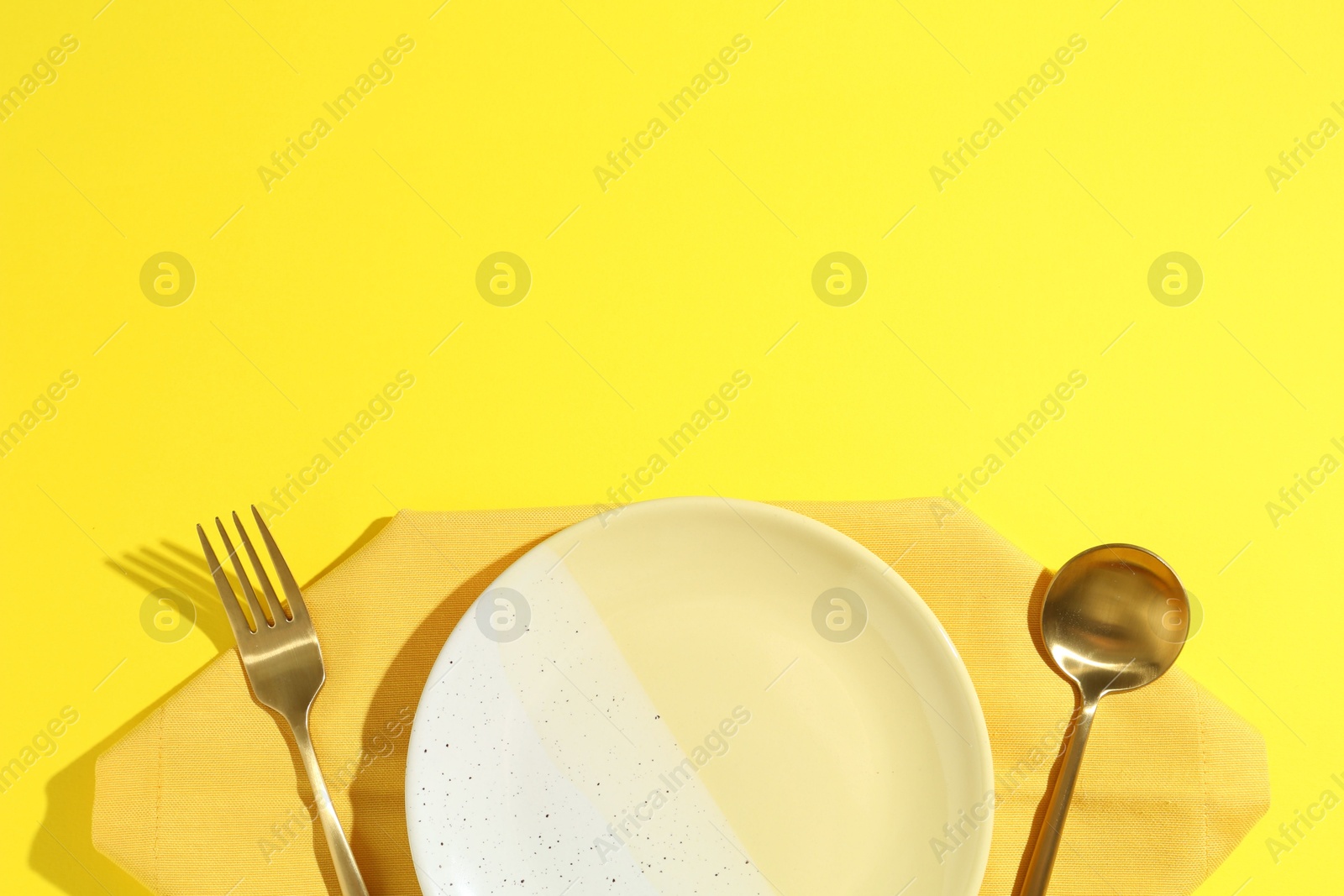 Stylish plate, cutlery and napkin on yellow background, flat lay. Space for text Photo of Stylish plate, cutlery and napkin on yellow background, flat lay. Space for text