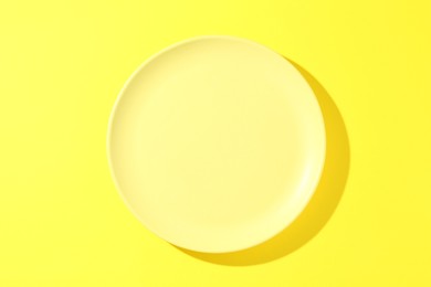 Photo of One stylish plate on yellow background, top view