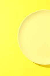 Photo of One stylish plate on yellow background, top view