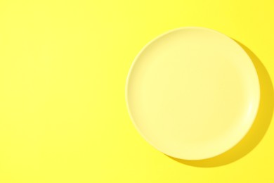 Photo of One stylish plate on yellow background, top view. Space for text