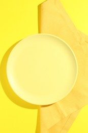 Photo of Stylish plate and napkin on yellow background, top view