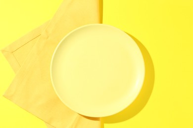 Photo of Stylish plate and napkin on yellow background, top view