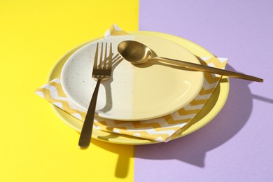 Photo of Stylish plates, cutlery and napkin on color background, closeup