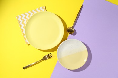 Photo of Stylish plates, cutlery and napkin on color background, flat lay