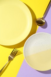 Photo of Stylish plates and cutlery on color background, flat lay