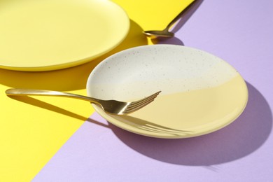 Photo of Stylish plates and cutlery on color background, closeup