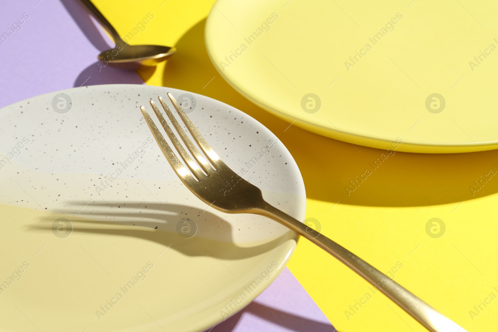 Stylish plates and cutlery on color background, closeup Photo of Stylish plates and cutlery on color background, closeup