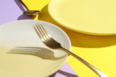Photo of Stylish plates and cutlery on color background, closeup