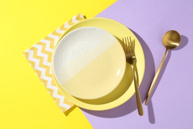 Photo of Stylish plates, cutlery and napkin on color background, flat lay