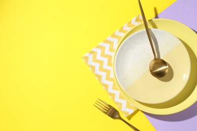 Photo of Stylish plates, cutlery and napkin on color background, flat lay. Space for text