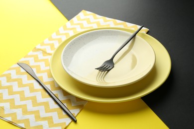 Photo of Stylish plates, cutlery and napkin on color background, closeup