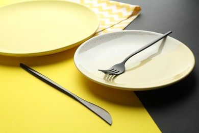 Photo of Stylish plates, cutlery and napkin on color background, closeup