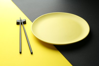 Photo of Stylish plate and chopsticks on color background, closeup