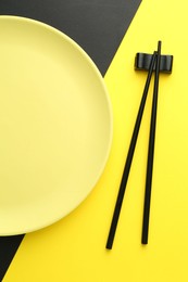 Photo of Stylish plate and chopsticks on color background, flat lay