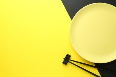 Photo of Stylish plate and chopsticks on color background, flat lay. Space for text
