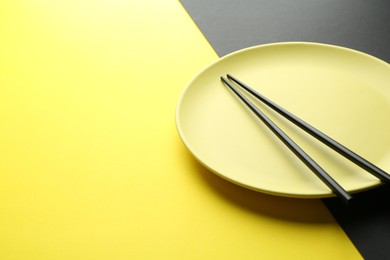 Photo of Stylish plate and chopsticks on color background, closeup. Space for text