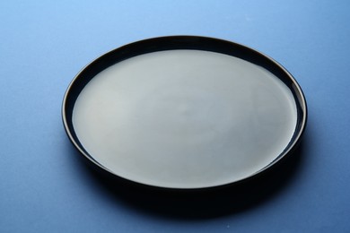 Photo of One stylish plate on blue background, closeup