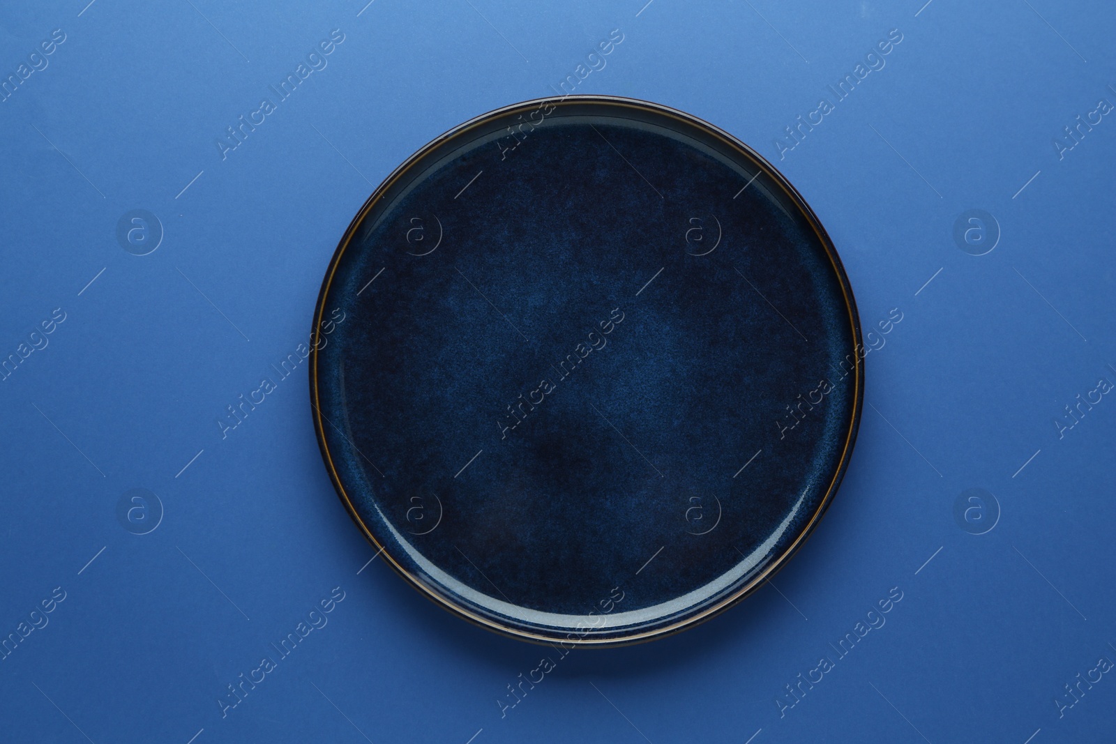 One stylish plate on blue background, top view Photo of One stylish plate on blue background, top view
