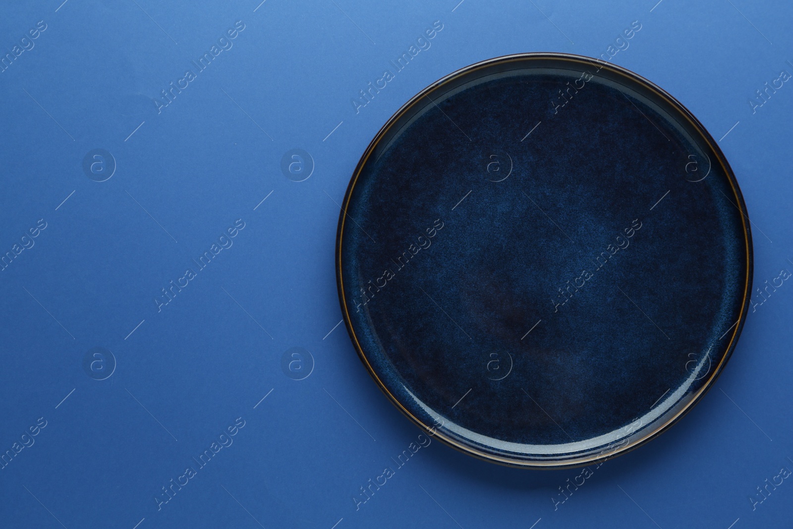 One stylish plate on blue background, top view. Space for text Photo of One stylish plate on blue background, top view. Space for text