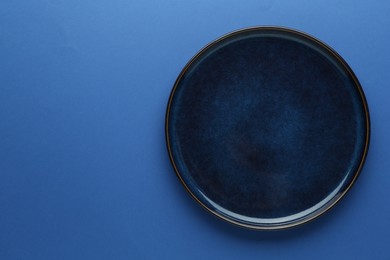 Photo of One stylish plate on blue background, top view. Space for text