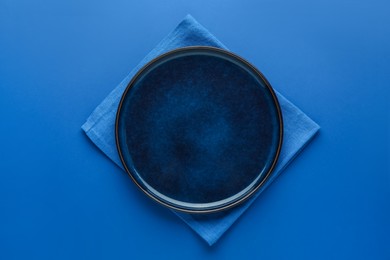 Photo of Stylish plate and napkin on blue background, top view