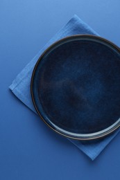 Photo of Stylish plate and napkin on blue background, top view