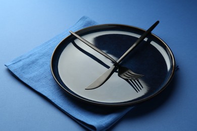 Photo of Stylish plate, cutlery and napkin on blue background, closeup