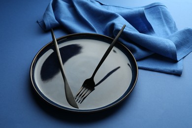 Photo of Stylish plate, cutlery and napkin on blue background, closeup