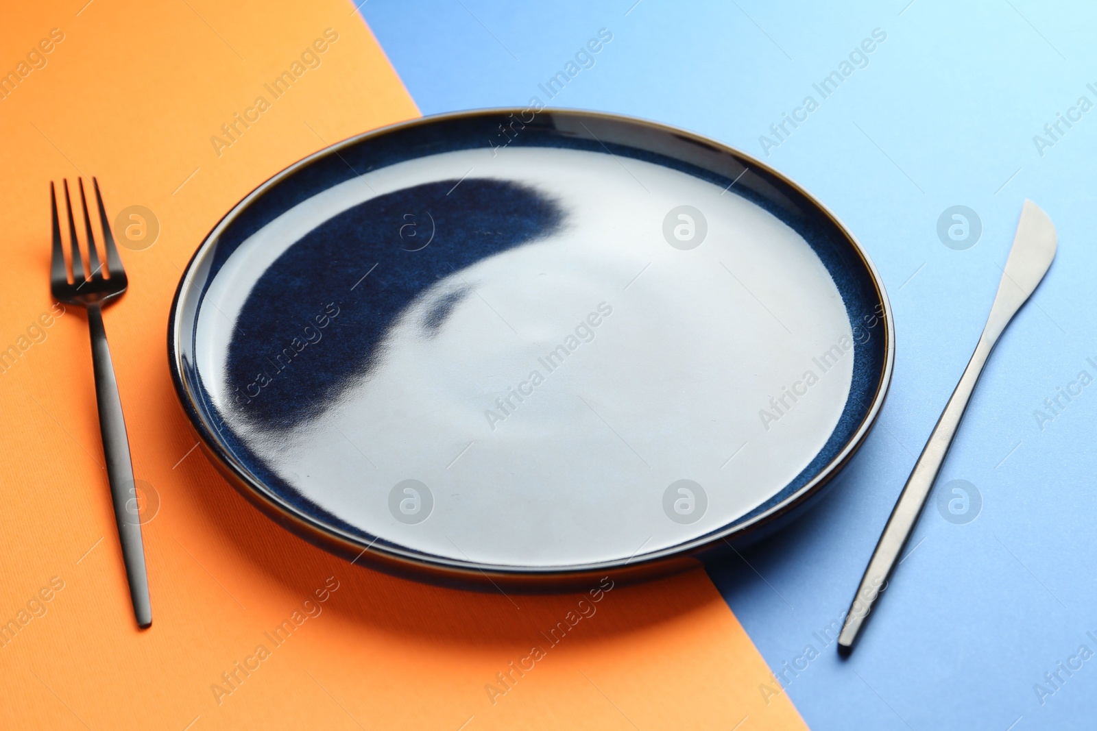 Stylish plate and cutlery on color background, closeup Photo of Stylish plate and cutlery on color background, closeup