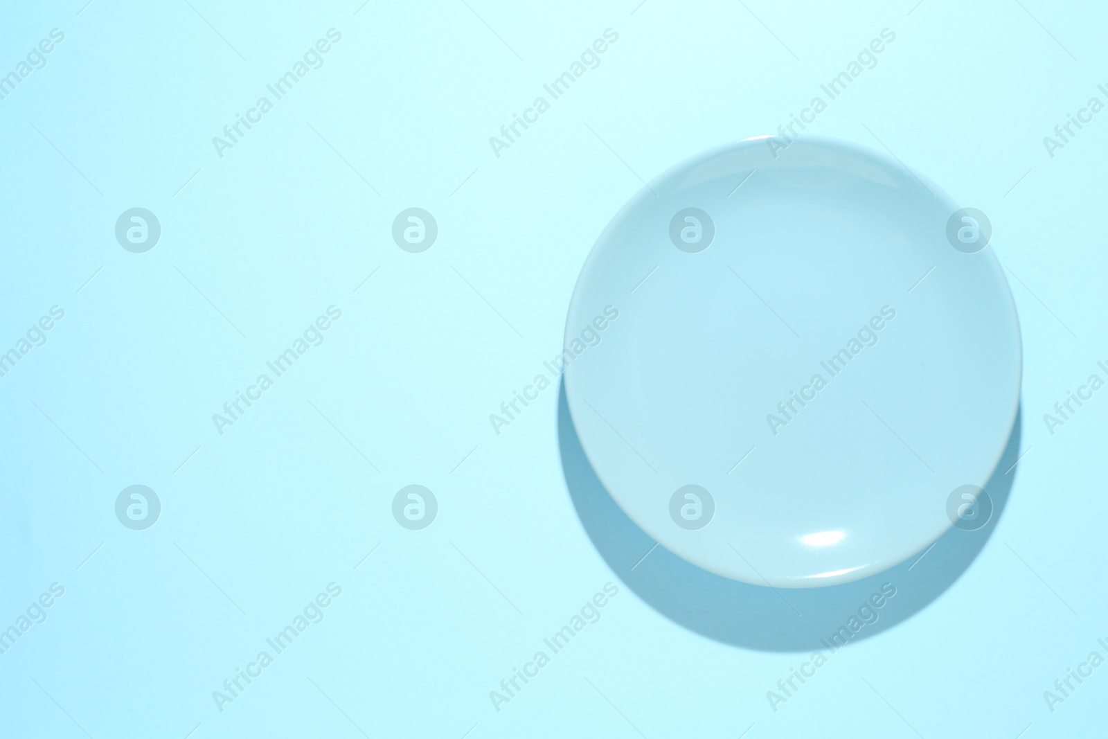 One stylish plate on light blue background, top view. Space for text Photo of One stylish plate on light blue background, top view. Space for text