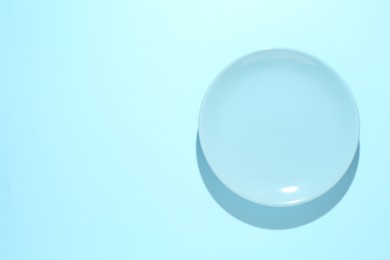 Photo of One stylish plate on light blue background, top view. Space for text