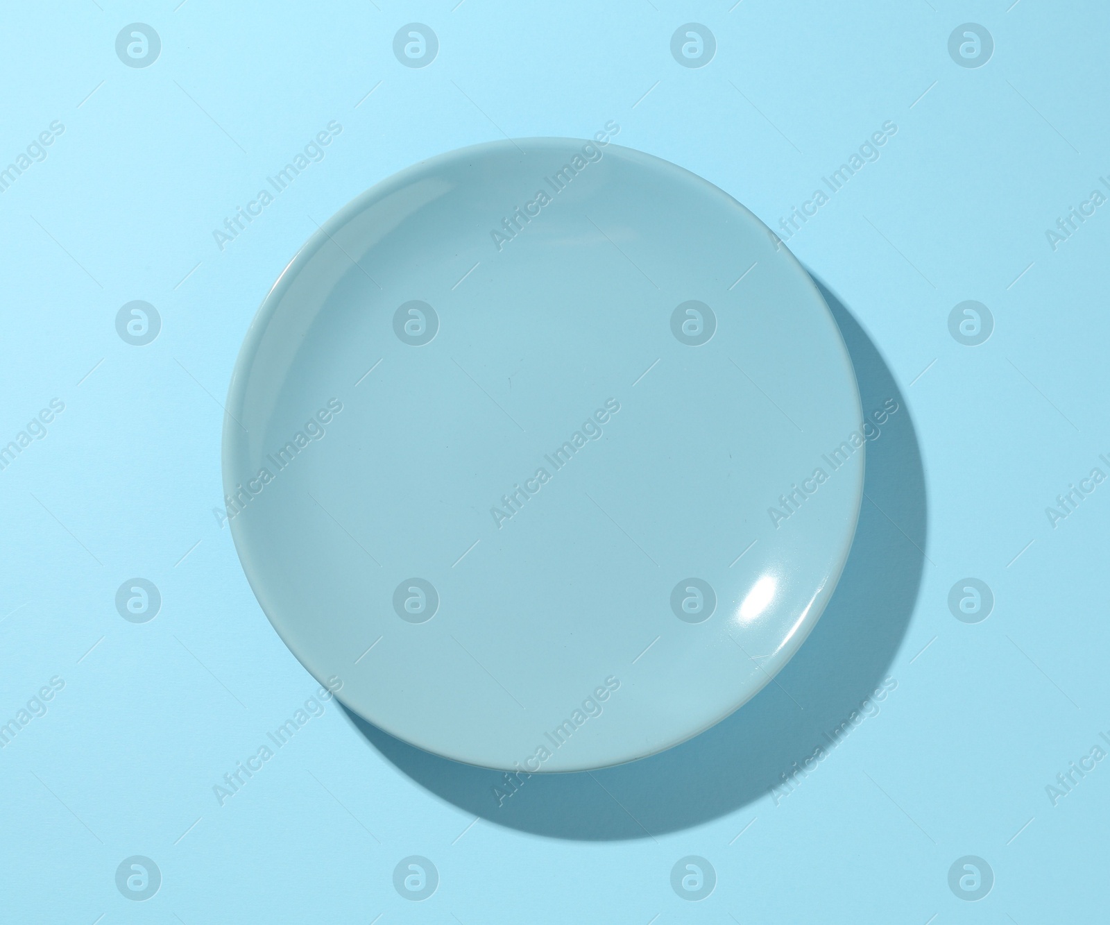 One stylish plate on light blue background, top view Photo of One stylish plate on light blue background, top view