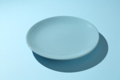 Photo of One stylish plate on light blue background, closeup