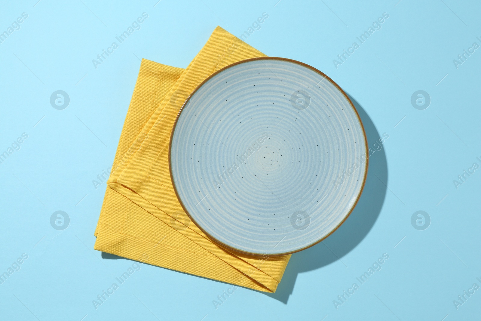 Stylish plate and napkin on light blue background, top view Photo of Stylish plate and napkin on light blue background, top view