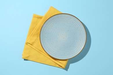 Photo of Stylish plate and napkin on light blue background, top view