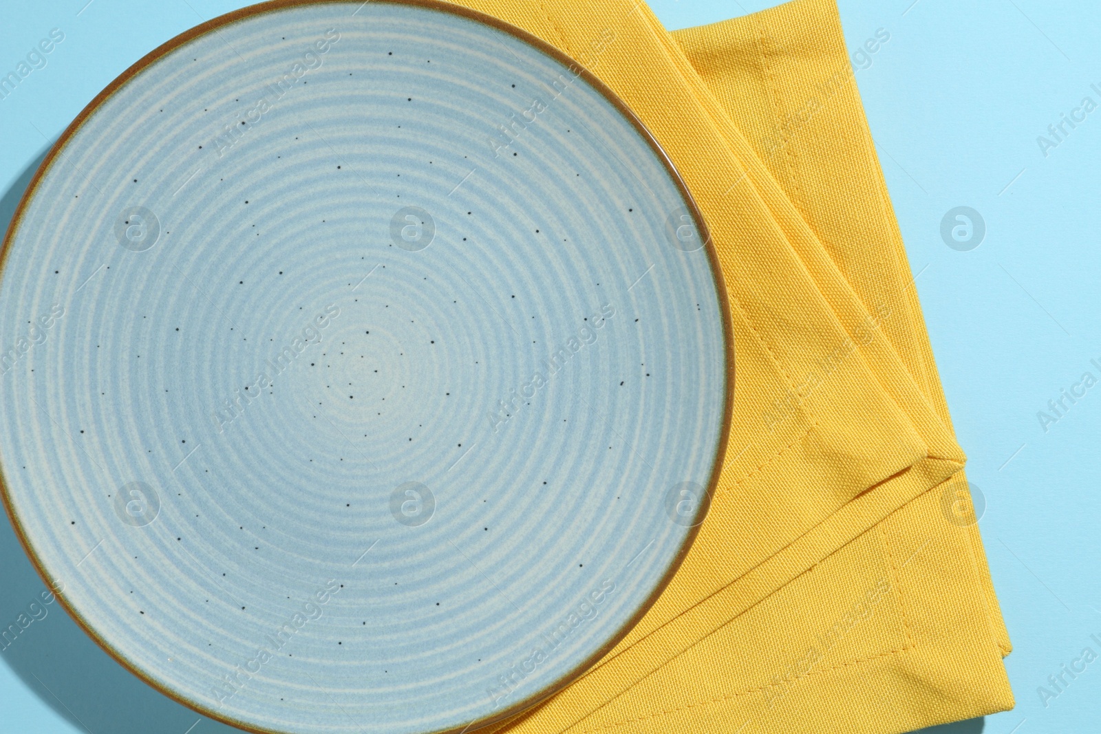 Stylish plate and napkin on light blue background, top view Photo of Stylish plate and napkin on light blue background, top view
