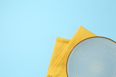 Photo of Stylish plate and napkin on light blue background, top view. Space for text