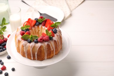 Photo of Delicious bundt cake with berries, glaze and mint on white wooden table, closeup. Space for text
