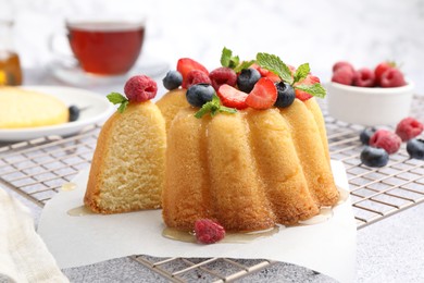 Photo of Tasty Bundt cake with berries, honey and mint on light grey table, closeup