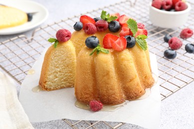 Photo of Tasty Bundt cake with berries, honey and mint on table, closeup