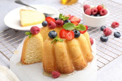 Photo of Tasty Bundt cake with berries, honey and mint on light grey table, closeup