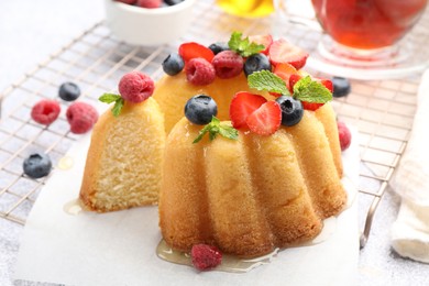 Photo of Tasty Bundt cake with berries, honey and mint on table, closeup