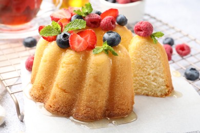 Photo of Tasty Bundt cake with berries, honey and mint on table, closeup